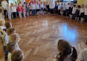 Dzieci śpiewają hymn Polski w postawie "na baczność"