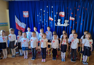 Dzieci śpiewają hymn Polski w postawie "na baczność"