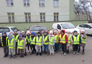 Dzieci stoją ustawione w pary przed budynkiem biblioteki