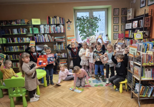 Grupa dzieci ogląda książki w kąciku czytelniczy dla dzieci