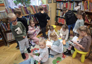 Grupa dzieci ogląda książki w kąciku czytelniczy dla dzieci