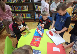 Grupa dzieci ogląda książki w kąciku czytelniczy dla dzieci