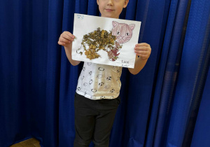 Chłopiec z pracą plastyczną wykonanę z materiału przyrodniczego