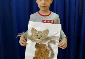 Chłopiec z pracą plastyczną wykonaną z materiału przyrodniczego