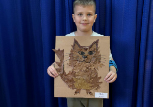 Chłopiec z pracą plastyczną wykonanę z materiału przyrodniczego