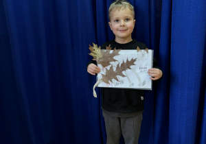 Chłopiec z pracą plastyczną wykonanę z materiału przyrodniczego