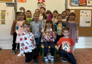 Dziewczynka w urodzinowej czapeczce z grupą dzieci