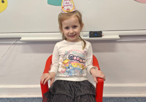 Dziewczynka siedzi na krzesełku i pozuje do zdjęcia