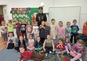 Dzieci stoją na dywanie i pozują wspólnie z górnikiem do zdjęcia