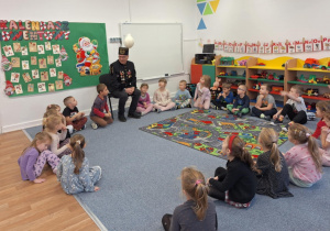 Dzieci siedzą na dywanie i słuchają opowieści górnika