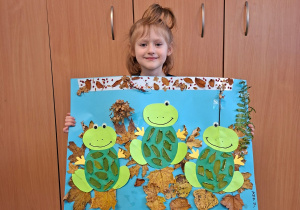 Dziecko pozuje do zdjęcia trzymając logo grupy przygotowane przez rodziców