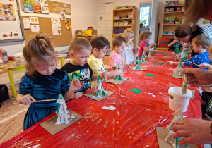 Dzieci wykonują choinkę z gipsowych elementów