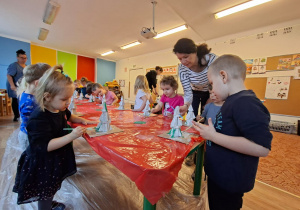 Dzieci wykonują choinkę z gipsowych elementów