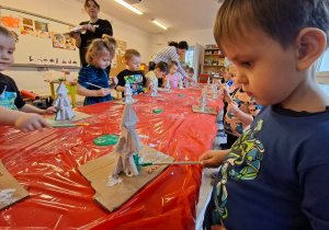 Dzieci wykonują choinkę z gipsowych elementów