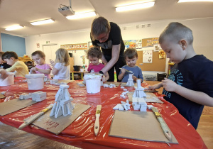 Dzieci wykonują choinkę z gipsowych elementów