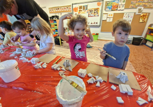 Dzieci wykonują choinkę z gipsowych elementów