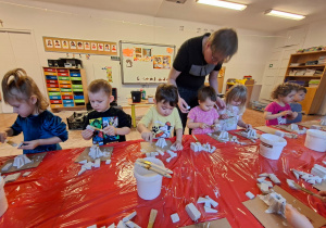 Dzieci wykonują choinkę z gipsowych elementów