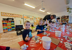 Dzieci wykonują choinkę z gipsowych elementów