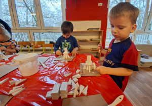 Dzieci wykonują choinkę z gipsowych elementów