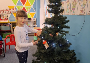 Dziewczynka wiesza ozdobę na choinkę