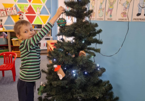 Chłopiec wiesza ozdobę na choinkę