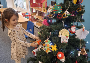 Dziewczynka wiesza ozdobę na choinkę