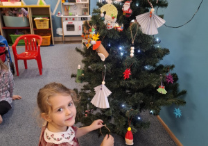 Dziewczynka wiesza ozdobę na choinkę