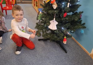 Chłopiec wiesza ozdobę na choinkę