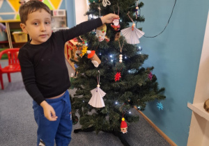 Chłopiec wiesza ozdobę na choinkę