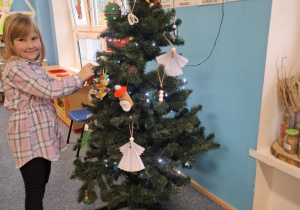 Dziewczynka wiesza ozdobę na choinkę