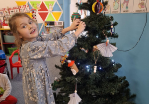 Dziewczynka wiesza ozdobę na choinkę