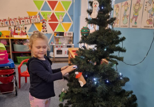 Dziewczynka wiesza ozdobę na choinkę