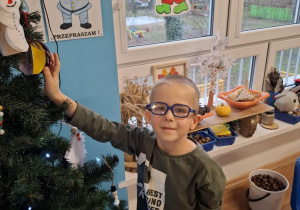 Chłopiec wiesza ozdobę na choinkę