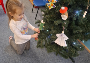 Dziewczynka wiesza ozdobę na choinkę