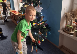 Chłopiec wiesza ozdobę na choinkę