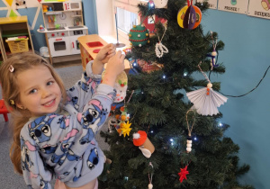 Dziewczynka wiesza ozdobę na choinkę