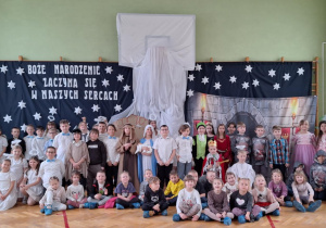 Przedszkolaki wraz z uczniami pozują do zdjęcia na tle świątecznej dekoraji