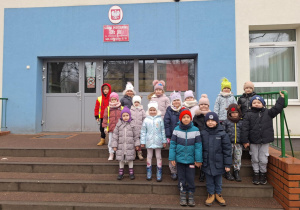 Dzieci pozują do zdjęcia przed szkołą podstawową