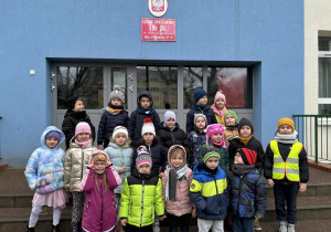 Grupa dzieci stoi przed szkołą