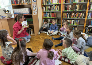 Grupa dzieci siedzi przed panią z książką