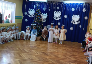 Trzy dziewczynki w strojach aniołów śpiewają