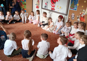 Dzieci z panią siedzą na dywanie