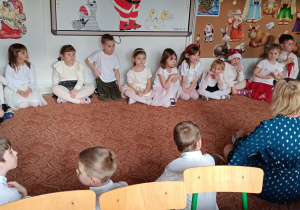 Dzieci z panią siedzą na dywanie