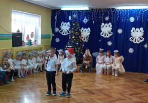 dwóch chłopców z mikrofonem, wkoło dzieci w strojach postaci z jasełek