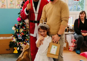 Dziewczynka z tatą pozuje do zjęcia z Mikołajem