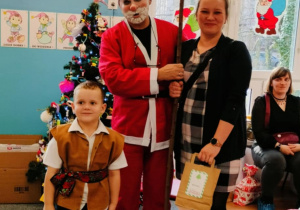 Chłopiec z mamą pozuje do zdjęcia z Mikołajem