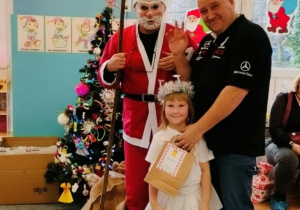 Dziewczynka z tatą pozuje do zjęcia z Mikołajem