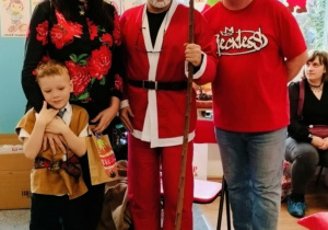 Chłopiec z rodzicami pozuje do zdjęcia z Mikołajem