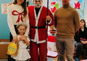 Dziewczynka z rodzicami pozuje do zdjęcia z Mikołajem