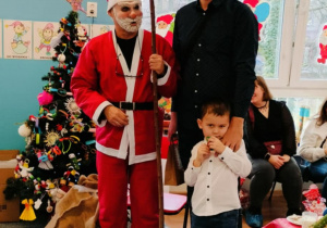 Chłopiec z tatą pozuje do zdjęcia z Mikołajem